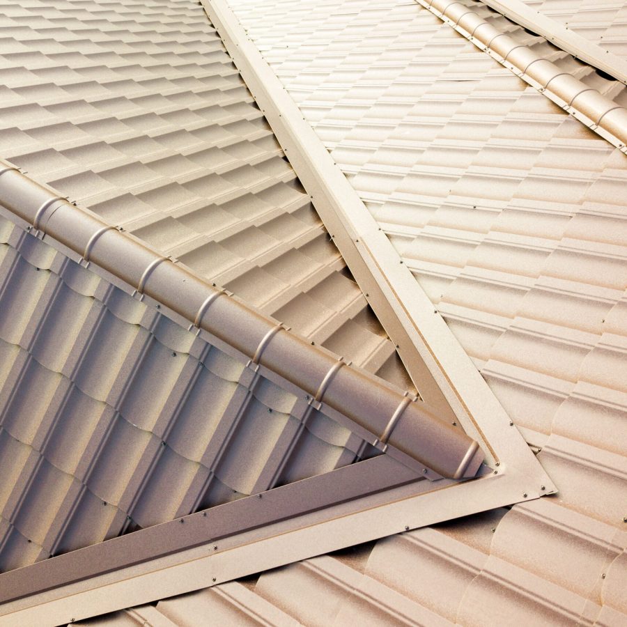 Aerial view of house roof structure covered with brown metal tile sheets.