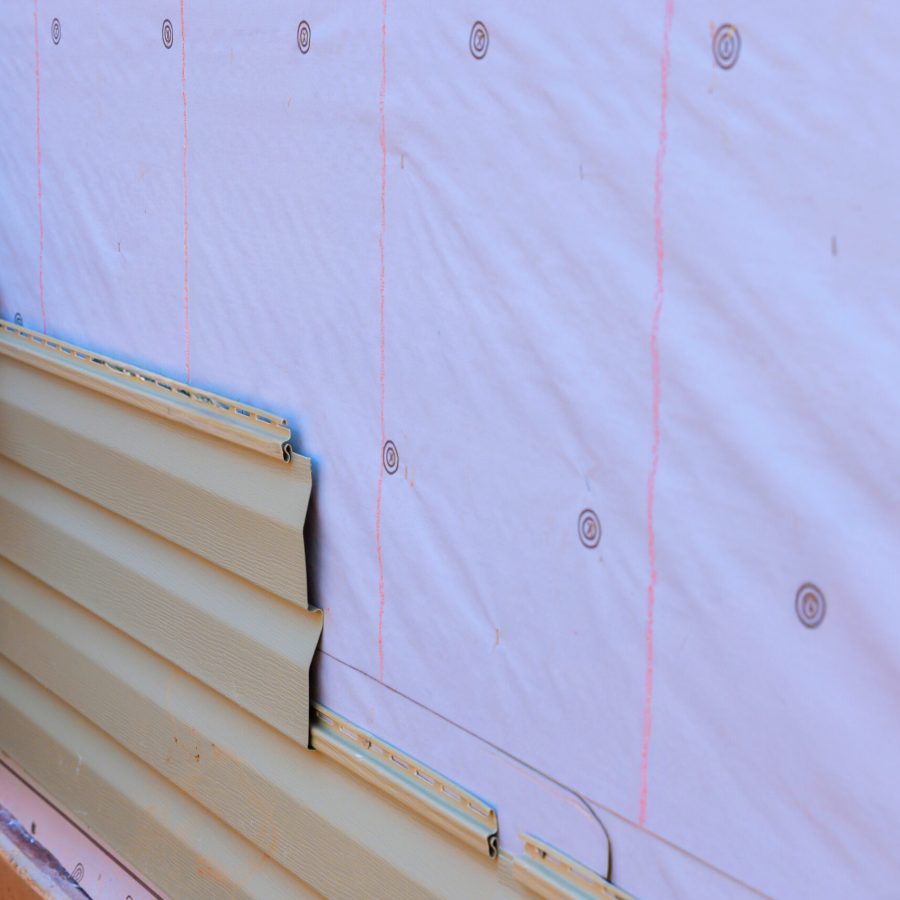 In process of installing vinyl siding on new home facade, handyman installs vinyl PVC siding